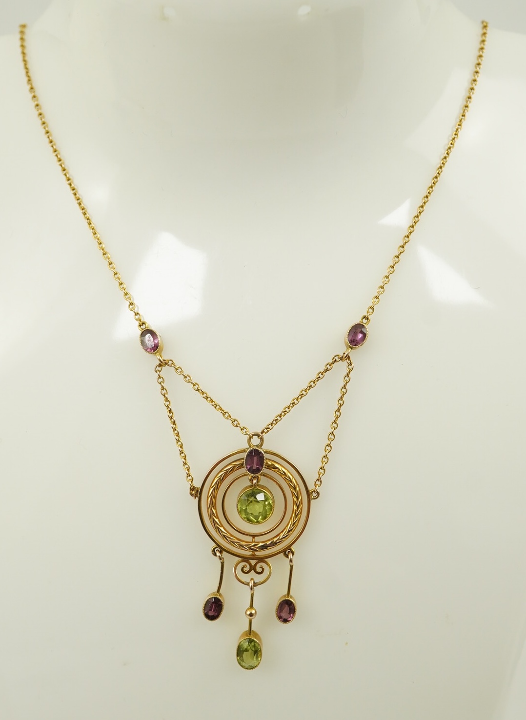 An Edwardian 9ct gold, peridot and garnet set drop pendant necklace, by Murrle Bennett & Co